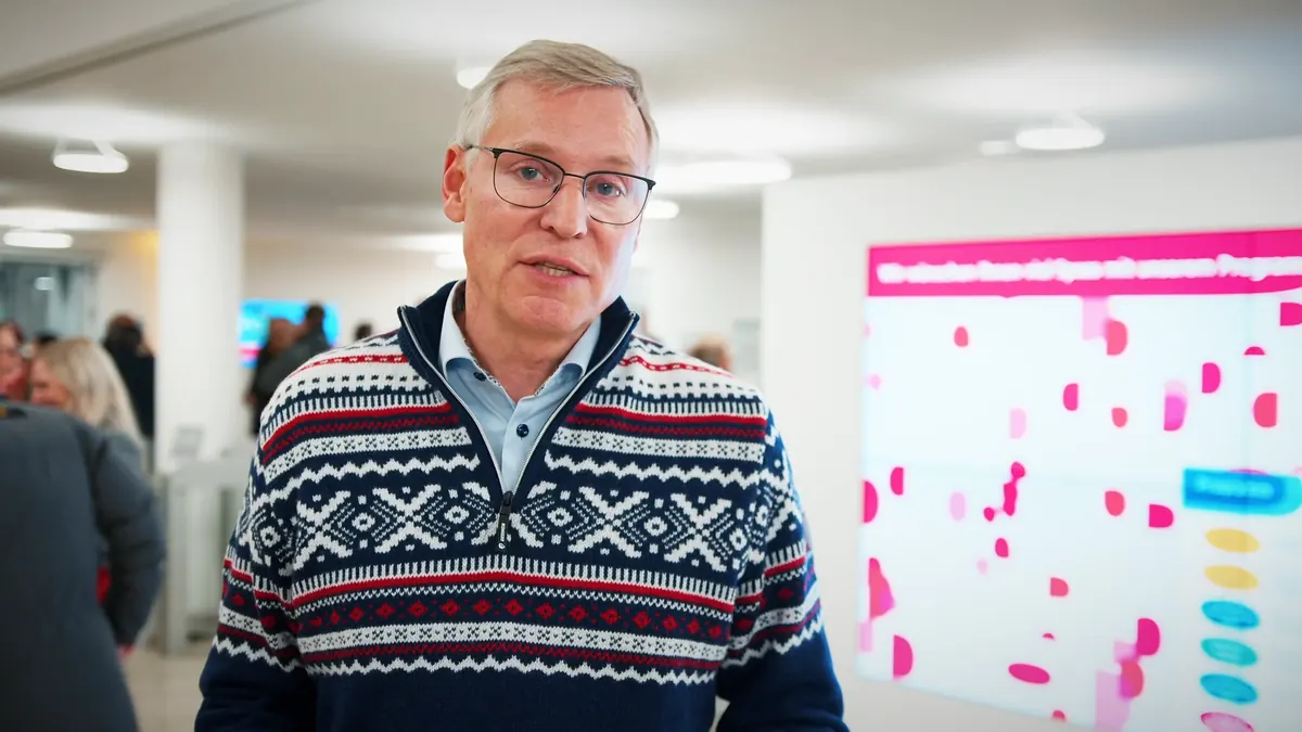Gast im Gespräch vor der Programmwand des Housewarmings