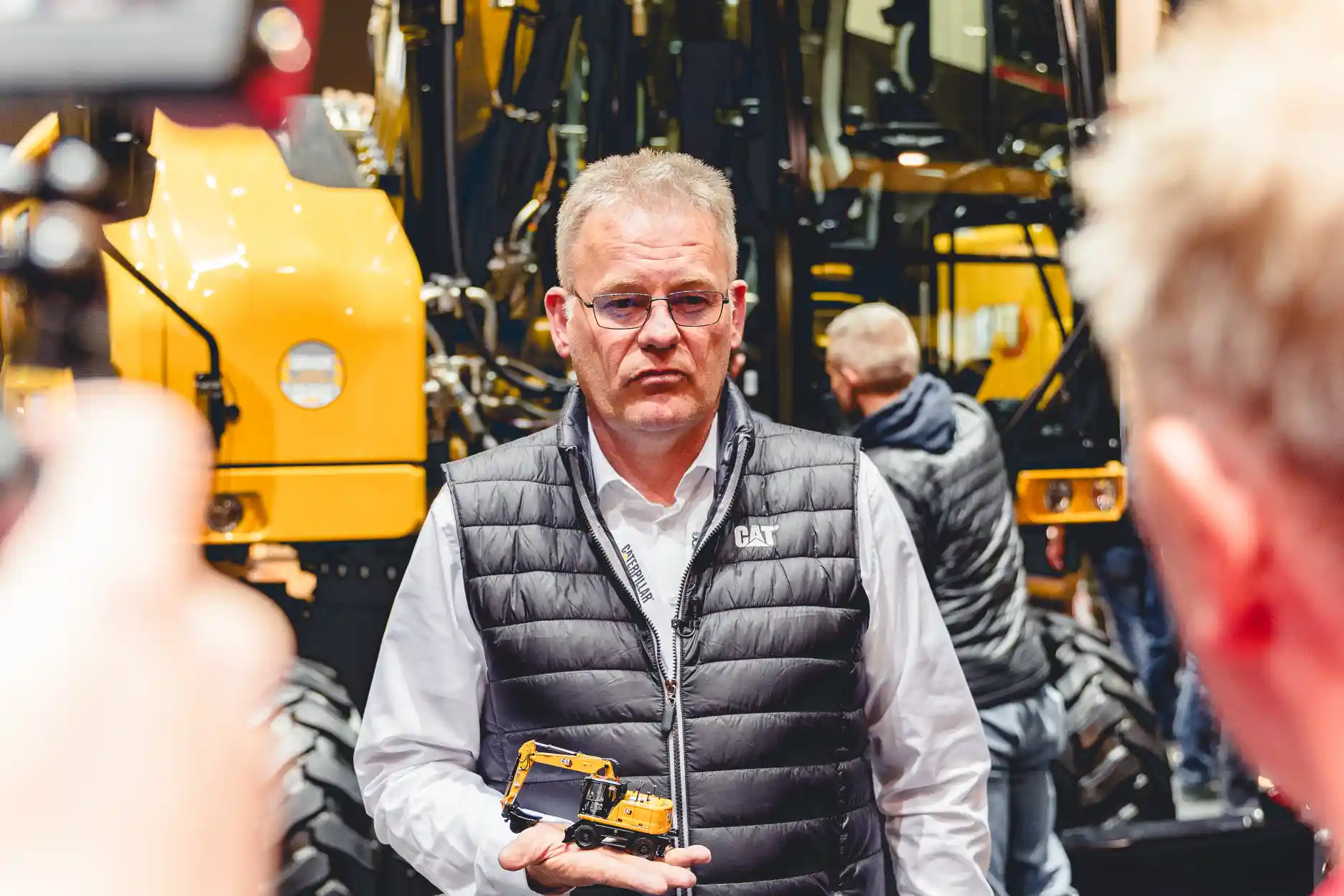 Interview mit Caterpillar-Mitarbeiter auf der Bauma 2025, Miniatur-Modell in der Hand