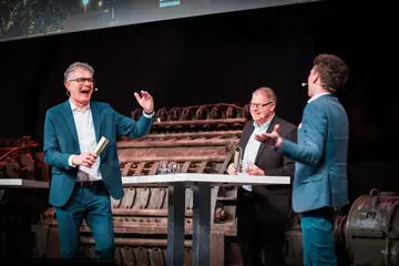 Zwei Preisträger lachen mit ihren Auszeichnungen auf der Bühne