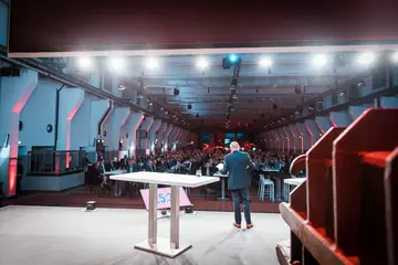 Blick von der Bühne über den Redner hinweg in die voll besetzte Halle