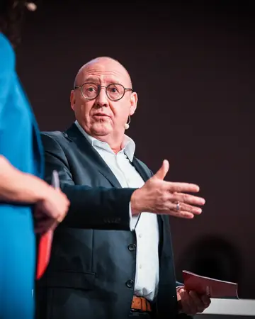 Redner gestikuliert im Gespräch mit der Moderatorin