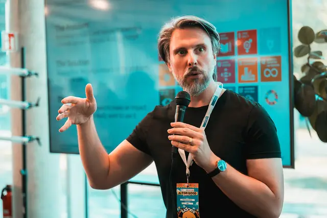 Redner mit Mikrofon erklärt die Aufgaben des Hackathons