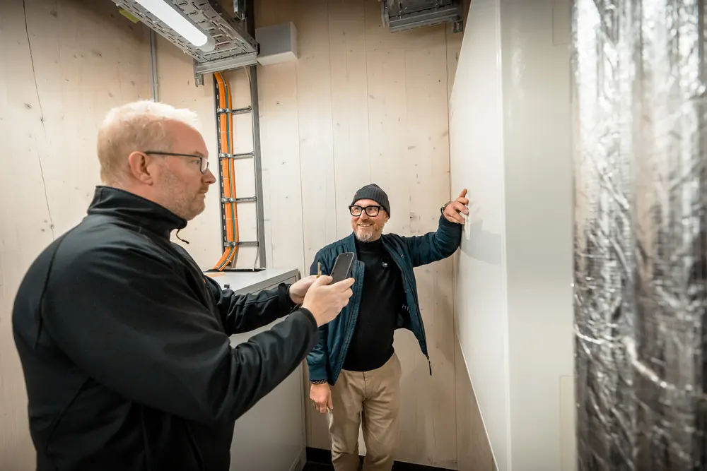 Zwei Männer begutachten die Installation an einer Wand im Neubau