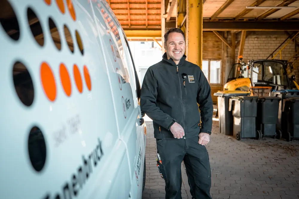 Monteur steht neben einem Transporter mit dem Fanenbruck-Logo