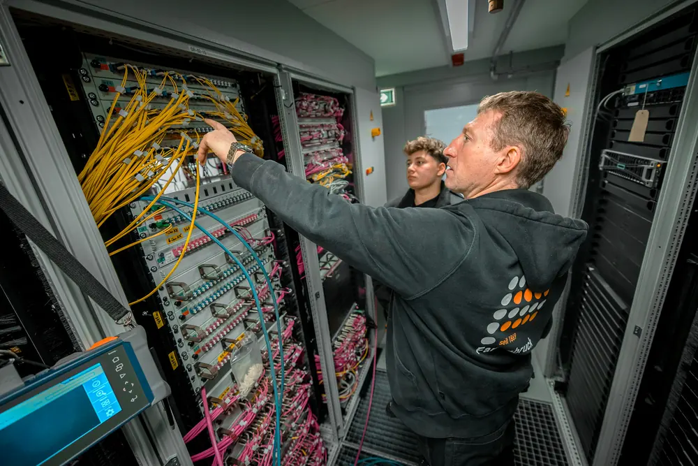 Techniker arbeitet an einem Glasfaser-Verteiler im Serverraum