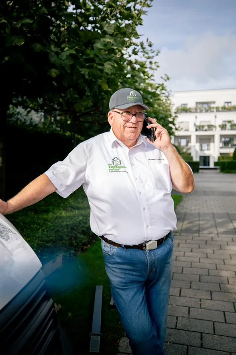 Fassadenretter am Telefon an einem Transporter vor einer Wohnanlage