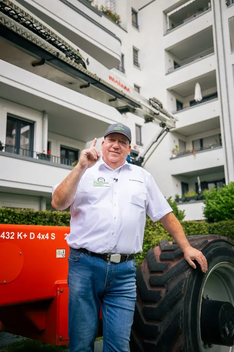 Fassadenretter neben dem Rad eines roten Hubsteigers