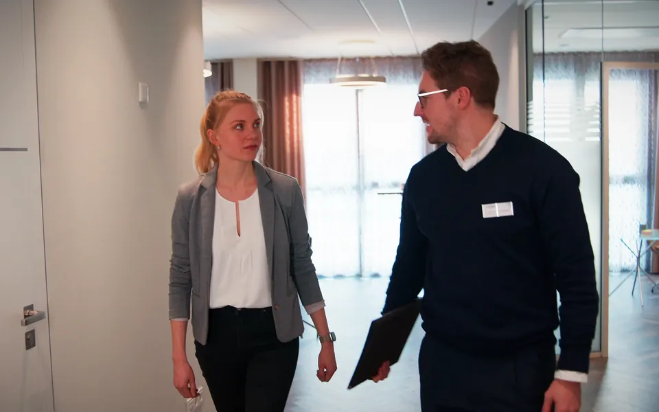 Ein Arzt begleitet eine Patientin über den Flur der Praxis