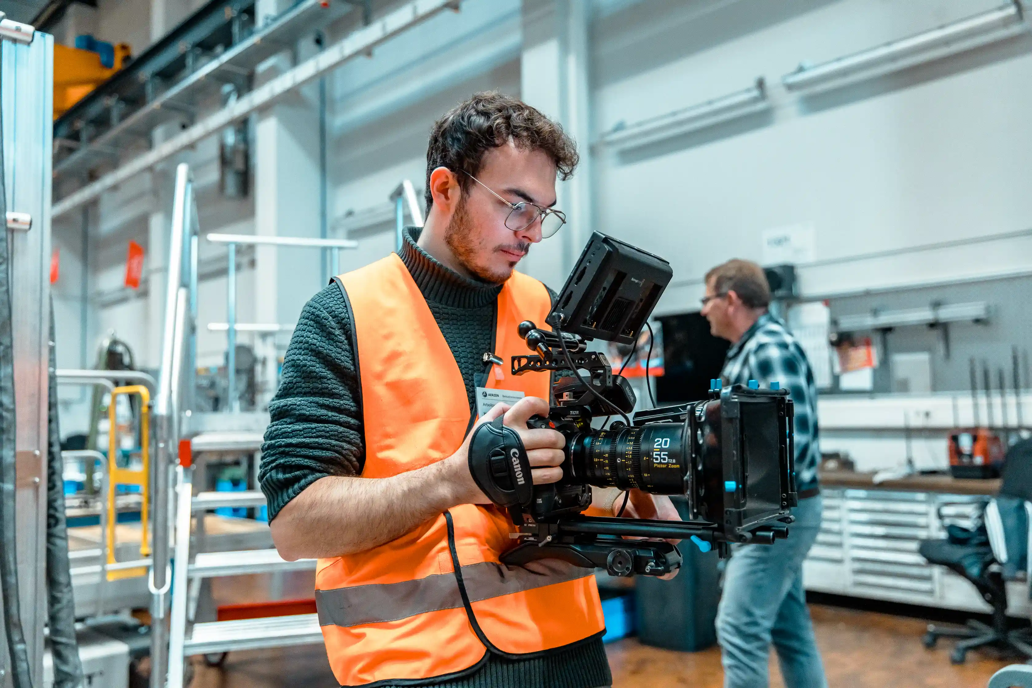 Behind the Scenes · CreativCube-Kameramann mit Warnweste in Fabrikhalle