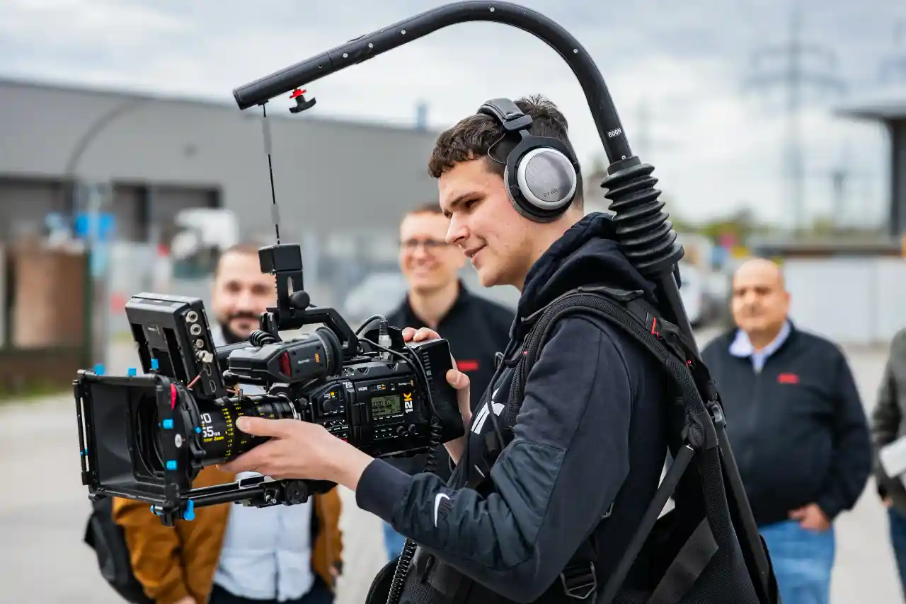 Behind the Scenes · CreativCube-Kameramann mit Crew im Industrieumfeld