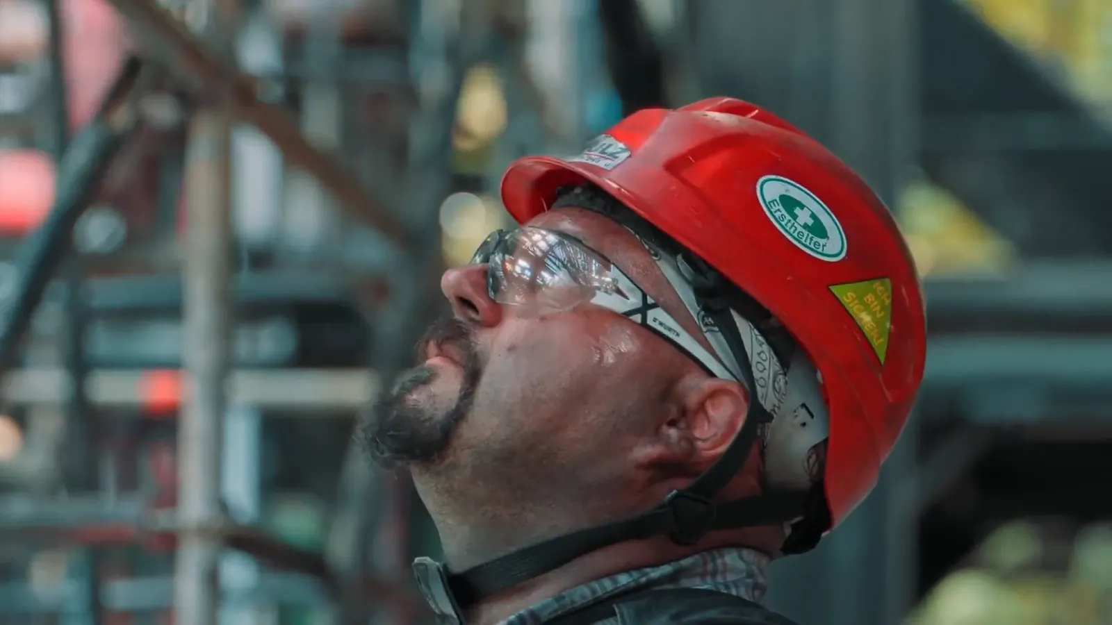 Gerüstbauer mit rotem Helm blickt auf der Baustelle nach oben