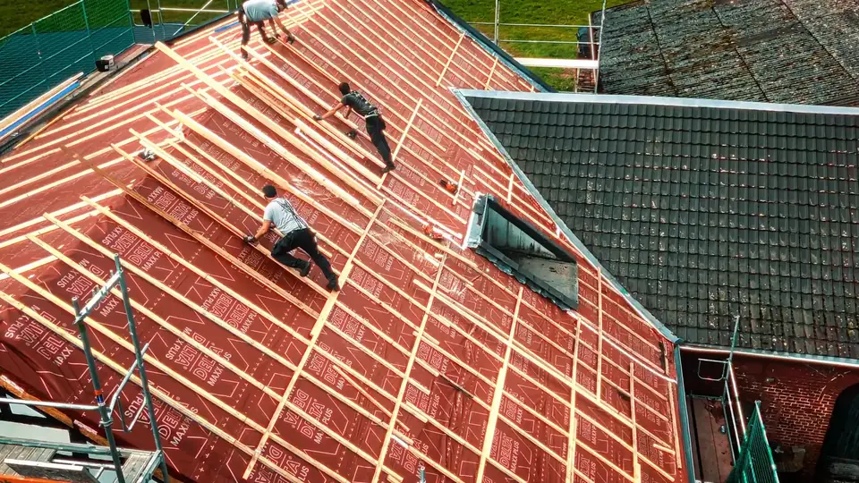 Dachdecker bei der Arbeit auf einem Steildach aus der Vogelperspektive