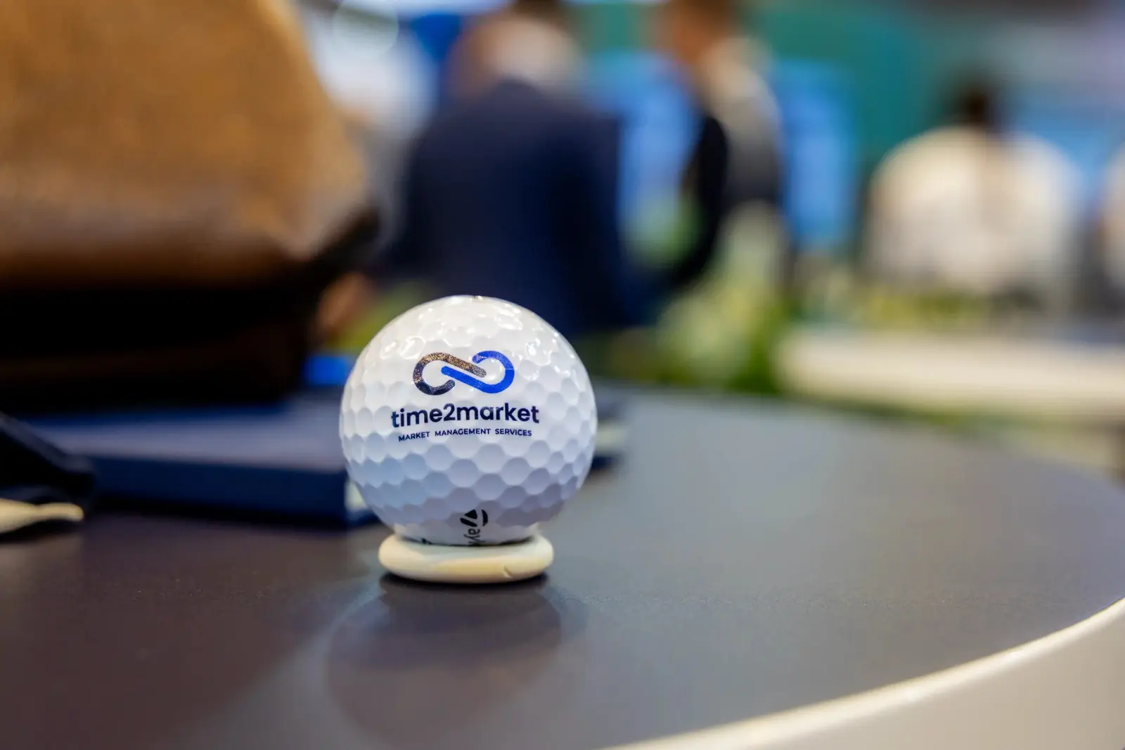 Golfball mit Logo von Time2Market auf einem Tisch am Stand