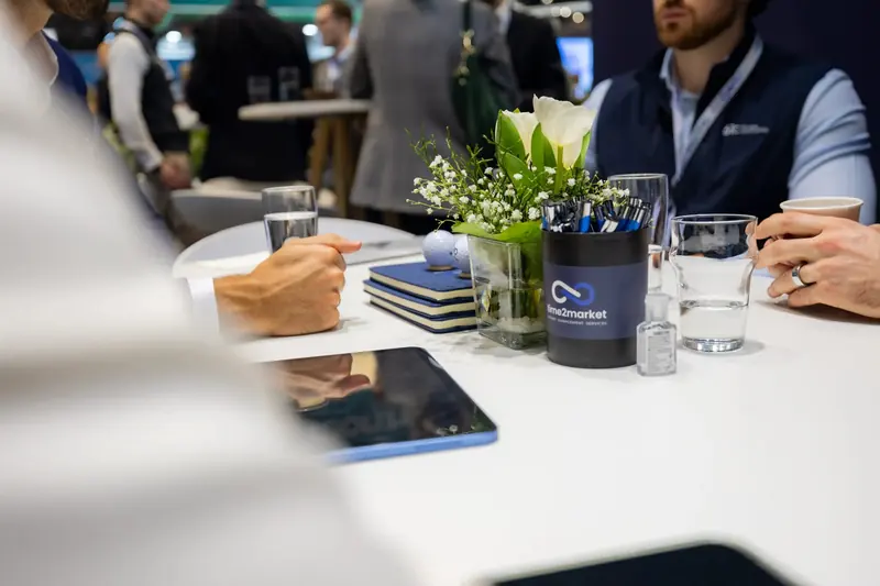 Tisch mit Notizbüchern, Wasser und Blumen bei einem Termin am Stand