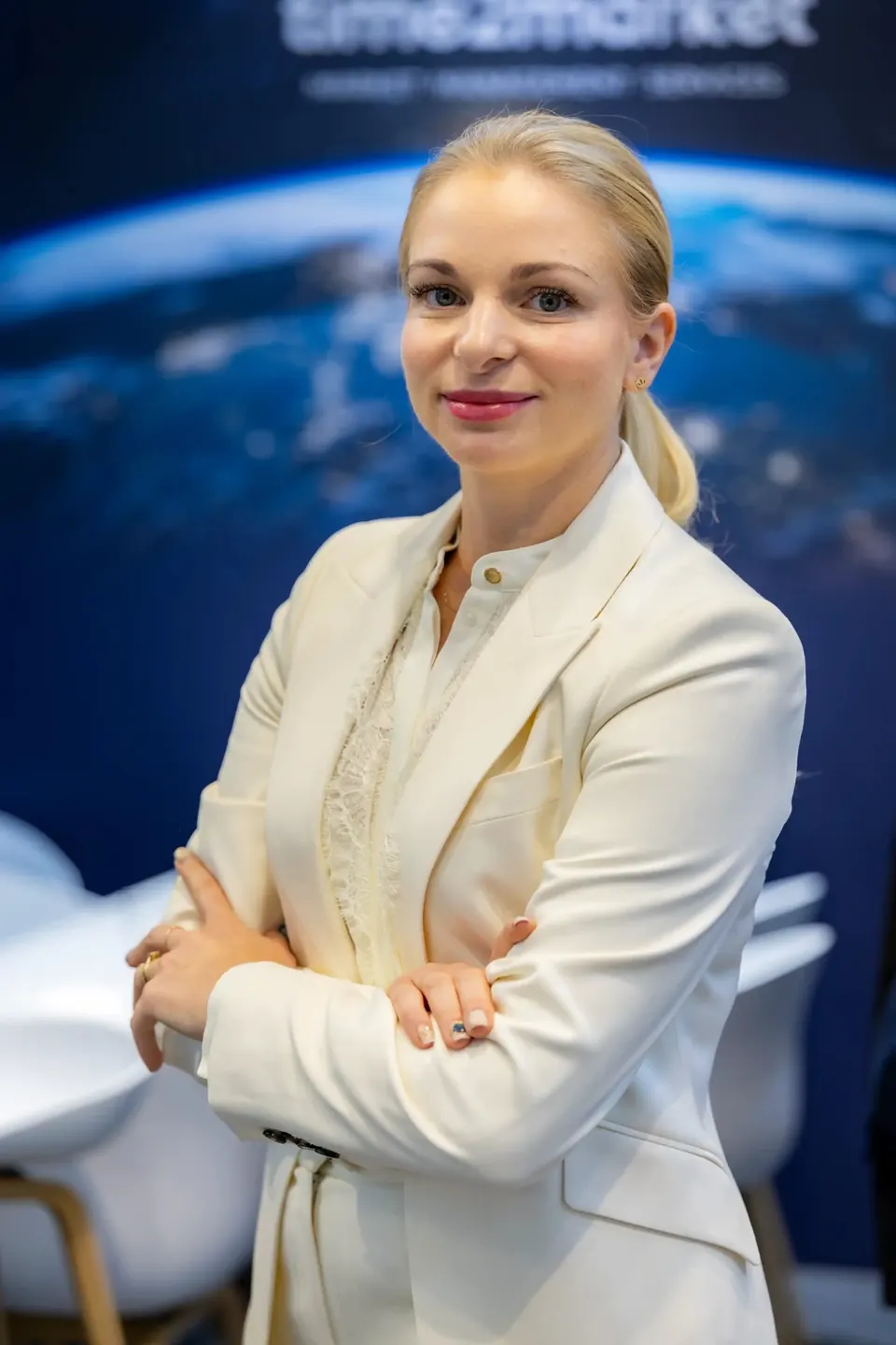 Porträt einer Mitarbeiterin von Time2Market vor der Rückwand mit der Erde aus dem All
