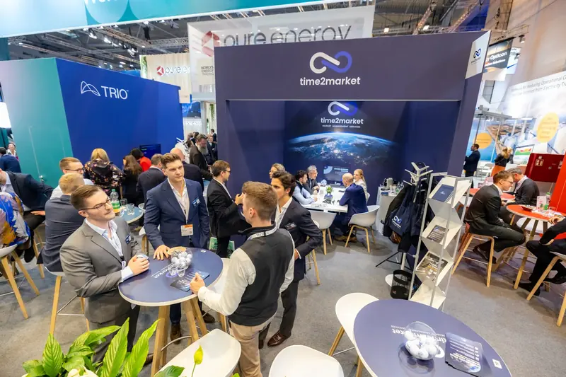 Stand von Time2Market vom Gang aus gesehen, mit Besuchern an den Tischen